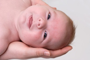 tête de bébé tenu par des mains